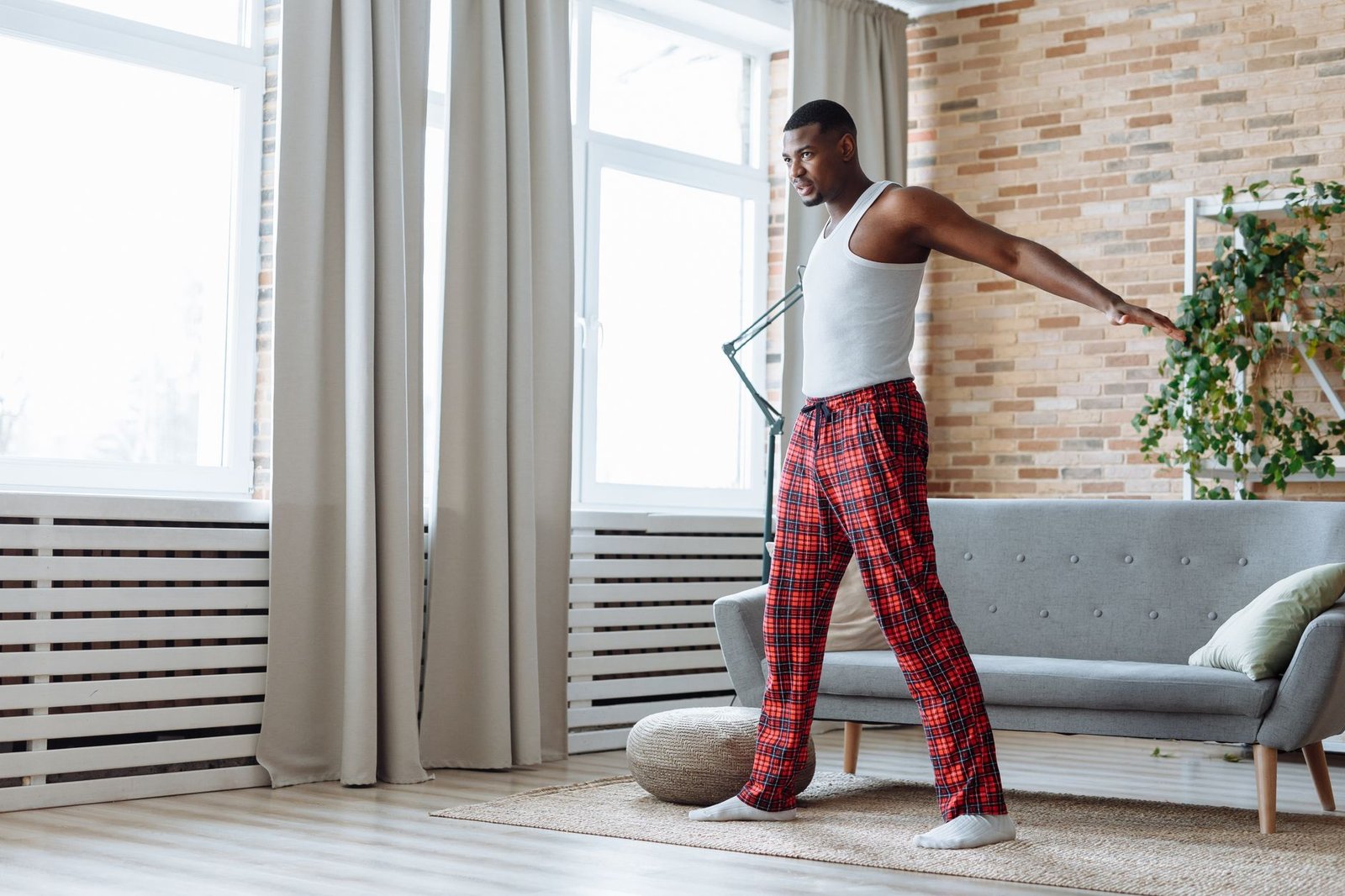 An adult man stretching indoors, in a modern living room with natural light.