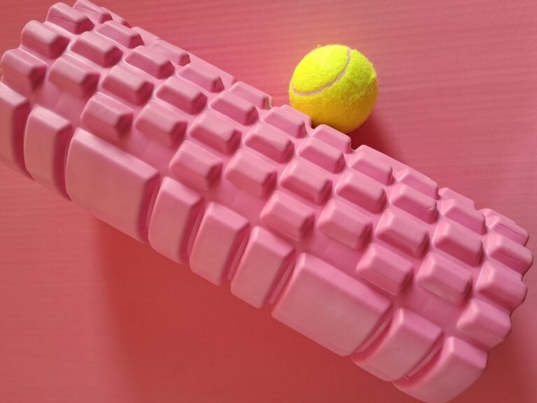 Bright pink foam roller and tennis ball on pink mat. Ideal for fitness themes.