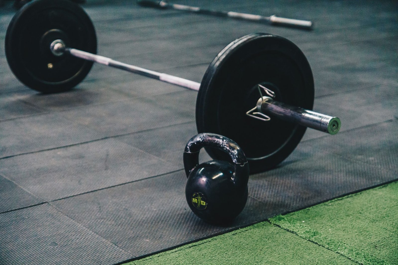 Barbell and kettlebell on gym floor, ideal for fitness and strength training themes.
