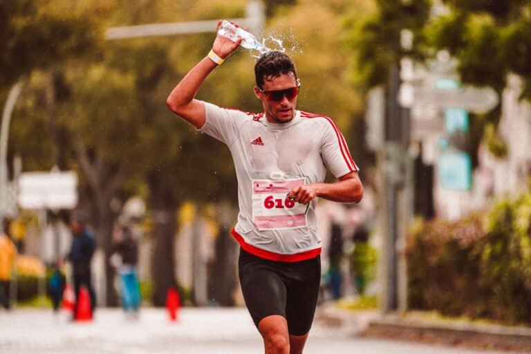 Marathon athlete pouring water over his head to cool down during an intense run.