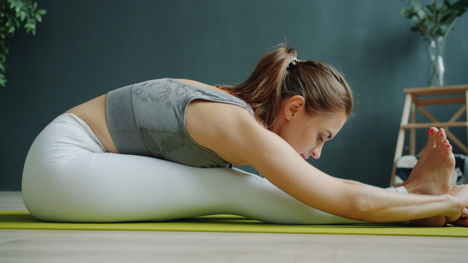 A woman in activewear stretching on a yoga mat indoors, focusing on wellness and fitness.