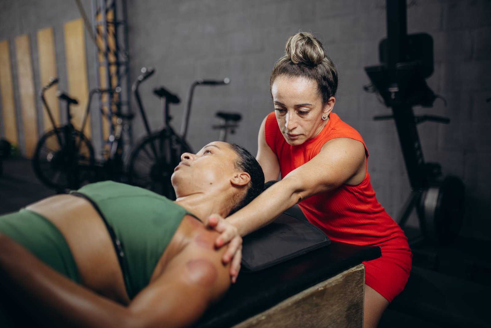 A therapist assists a woman with manual therapy to improve flexibility and mobility in a gym environment.