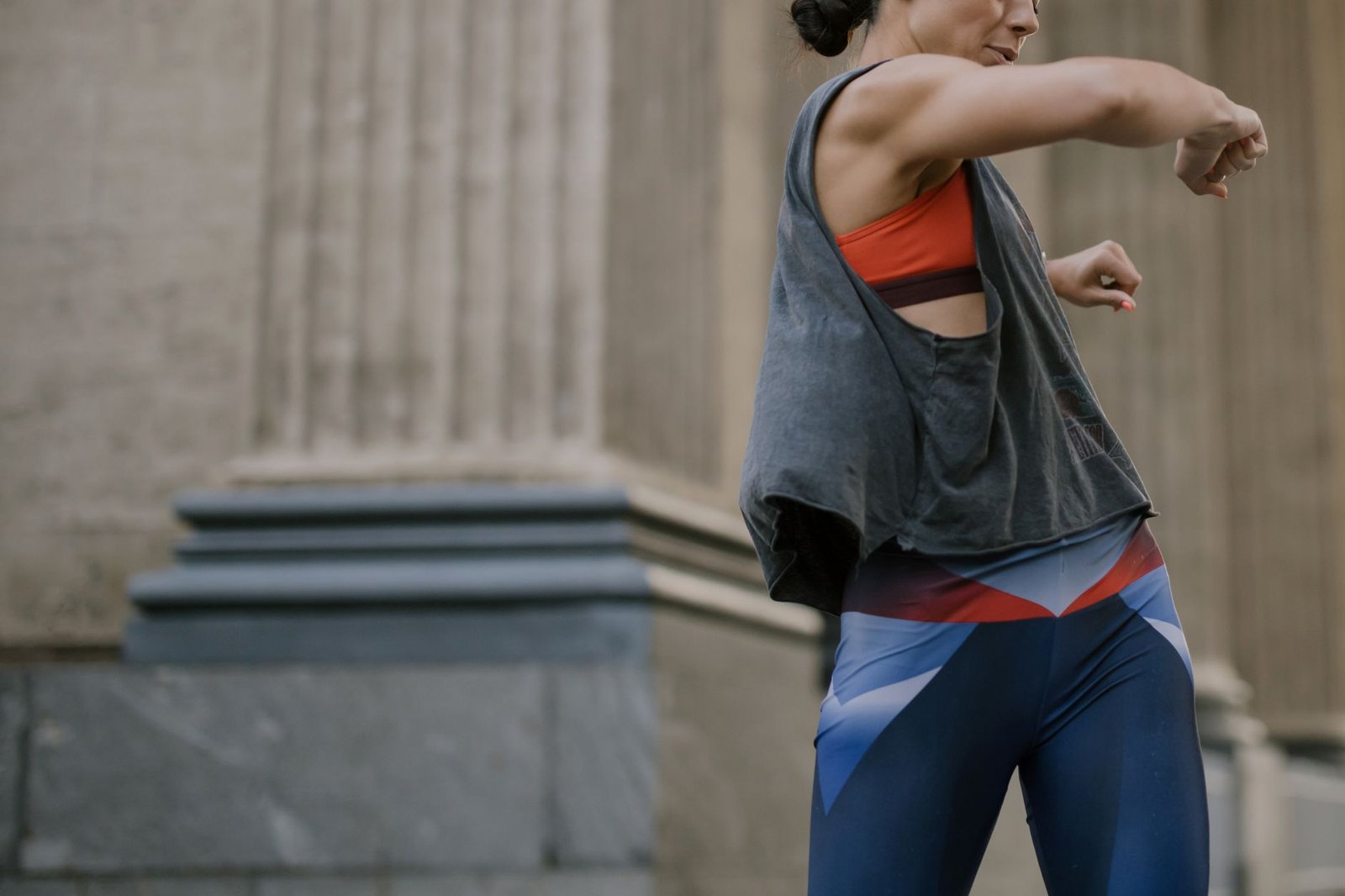 A woman wearing activewear performing a dynamic outdoor fitness routine.